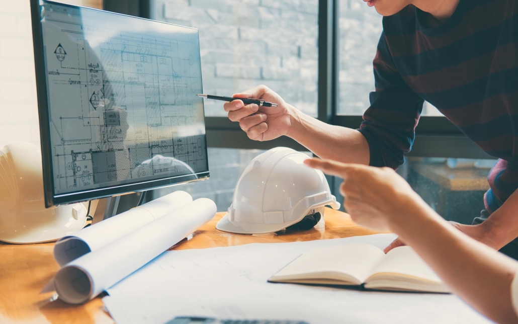 Two People In Office Looking Over Floorplan On Computer