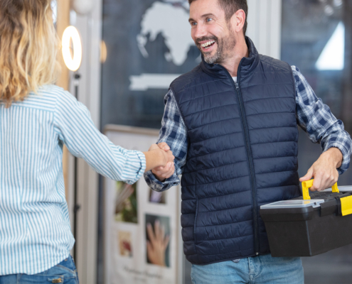 Plumber And Woman Shaking Hands At Home