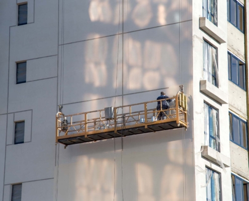 Workers Fixing Exterior Of Apartment Building
