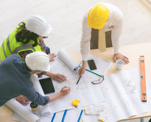 Group Of Workers Looking Over Construction Plans